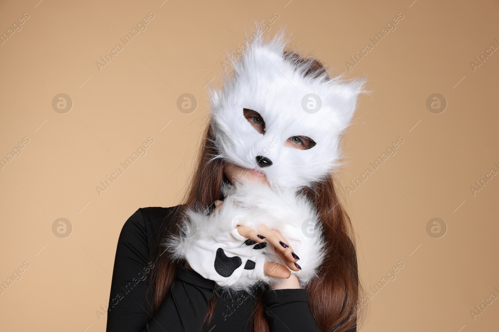 Photo of Quadrobics. Girl wearing cat mask and gloves on beige background