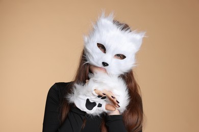 Photo of Quadrobics. Girl wearing cat mask and gloves on beige background