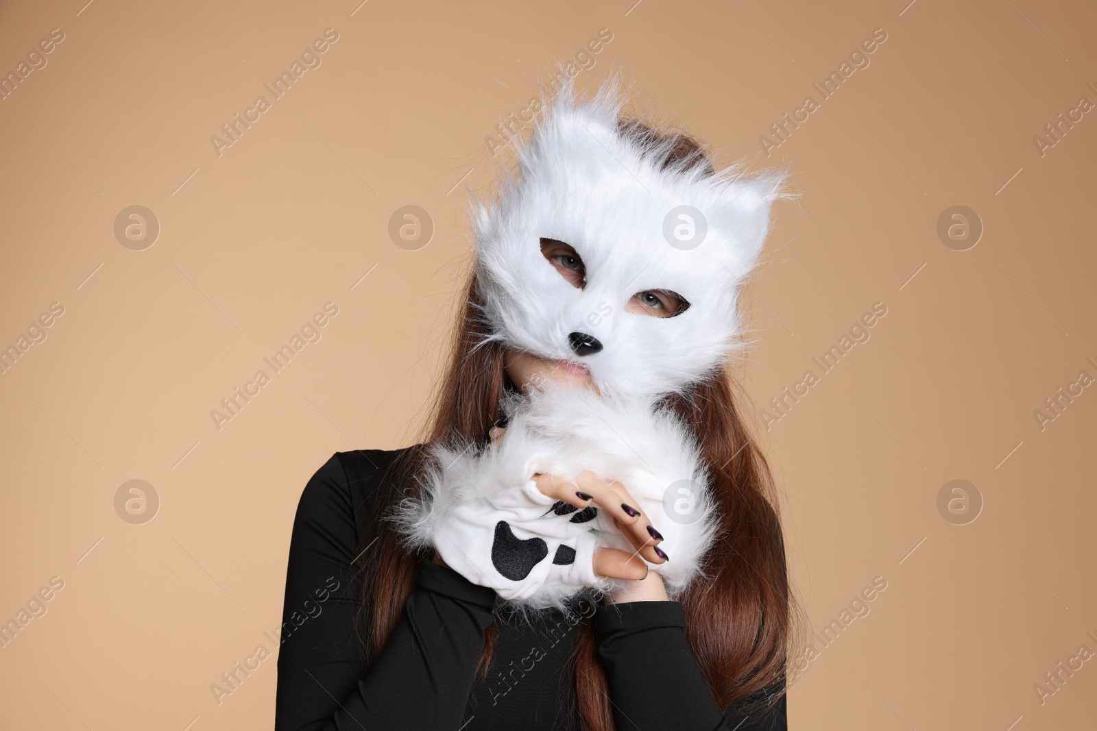 Photo of Quadrobics. Girl wearing cat mask and gloves on beige background