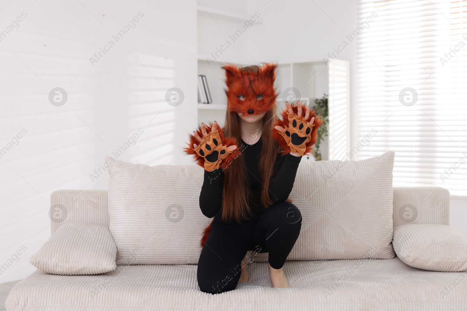 Photo of Quadrobics. Girl wearing fox mask and gloves on sofa at home