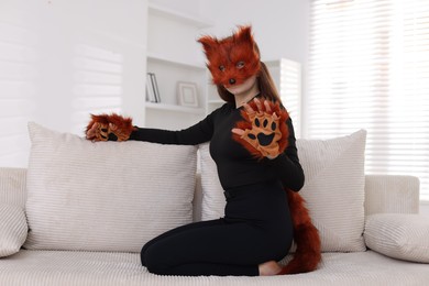 Photo of Quadrobics. Girl wearing fox mask, gloves and tail on sofa at home