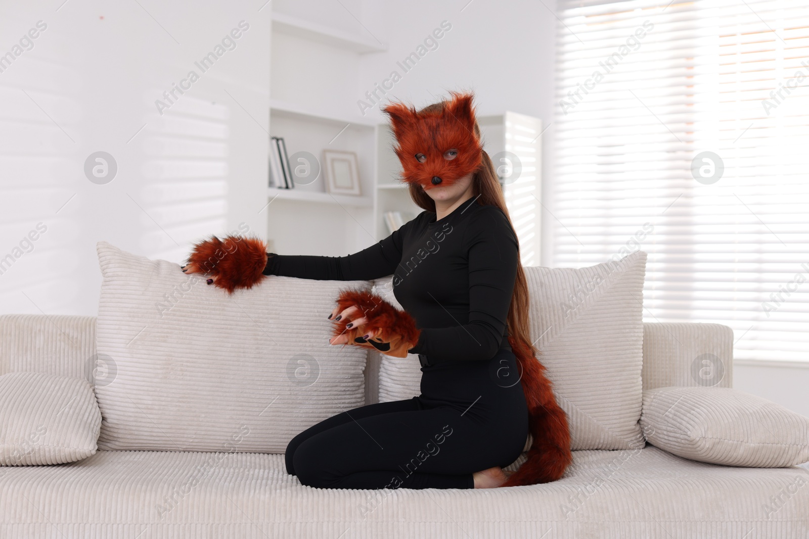 Photo of Quadrobics. Girl wearing fox mask, gloves and tail on sofa at home