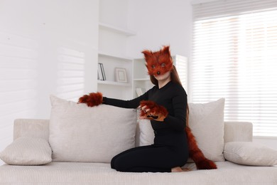 Photo of Quadrobics. Girl wearing fox mask, gloves and tail on sofa at home