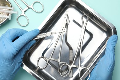 Photo of Doctor with different surgical tools on turquoise background, top view