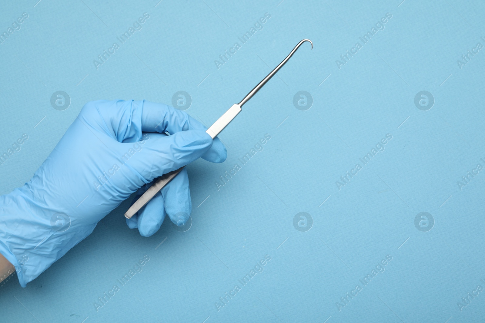 Photo of Doctor with surgical hook on light blue background, top view. Space for text