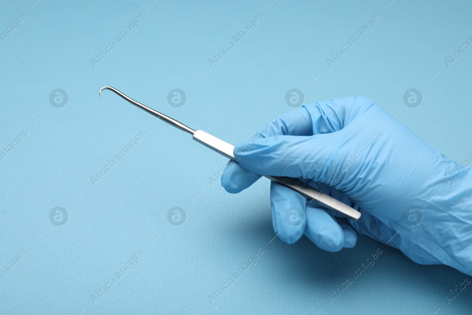 Photo of Doctor with surgical hook on light blue background, closeup. Space for text