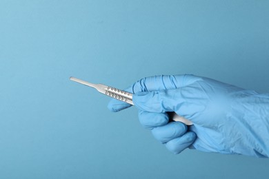 Photo of Doctor with surgical scalpel on light blue background, closeup. Space for text