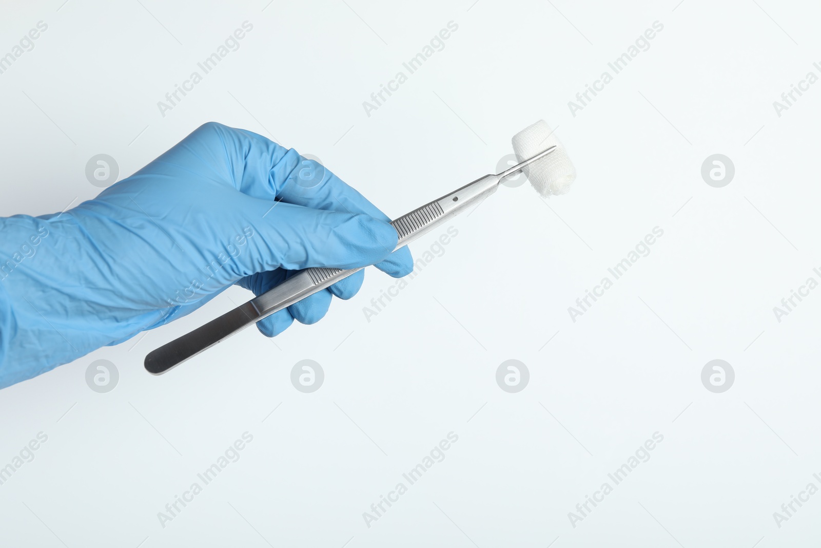 Photo of Doctor holding surgical tweezers with gauze on white background, closeup. Space for text