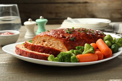 Photo of Delicious baked turkey meatloaf with vegetables served on wooden table, closeup