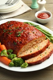 Photo of Delicious baked turkey meatloaf with vegetables served on wooden table, closeup