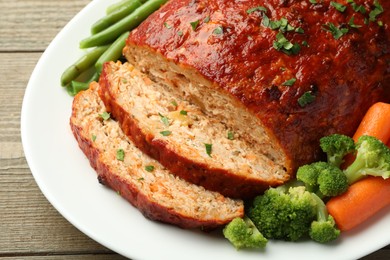 Photo of Delicious baked turkey meatloaf with vegetables on wooden table, closeup