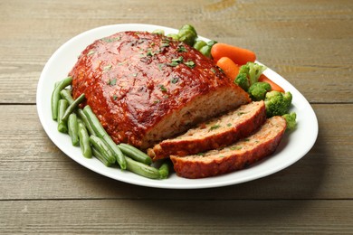 Photo of Delicious baked turkey meatloaf with vegetables on wooden table, closeup