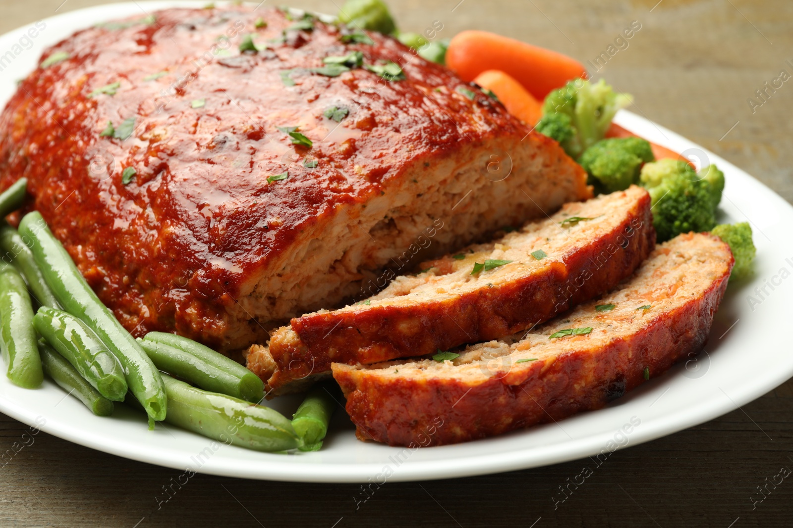 Photo of Delicious baked turkey meatloaf with vegetables on table, closeup