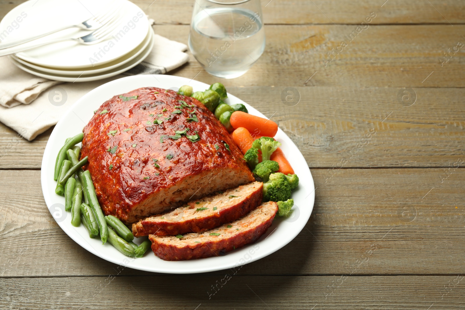 Photo of Delicious baked turkey meatloaf with vegetables served on wooden table, space for text