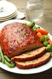 Photo of Delicious baked turkey meatloaf with vegetables on wooden table, closeup