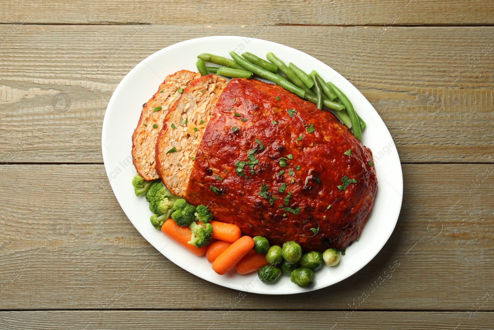 Photo of Delicious baked turkey meatloaf with vegetables on wooden table, top view