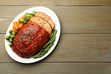 Photo of Delicious baked turkey meatloaf with vegetables on wooden table, top view. Space for text