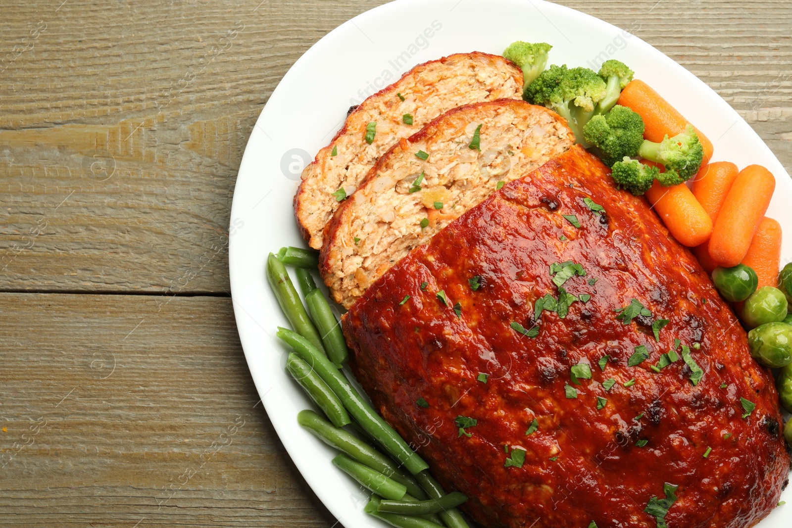 Photo of Delicious baked turkey meatloaf with vegetables on wooden table, top view. Space for text