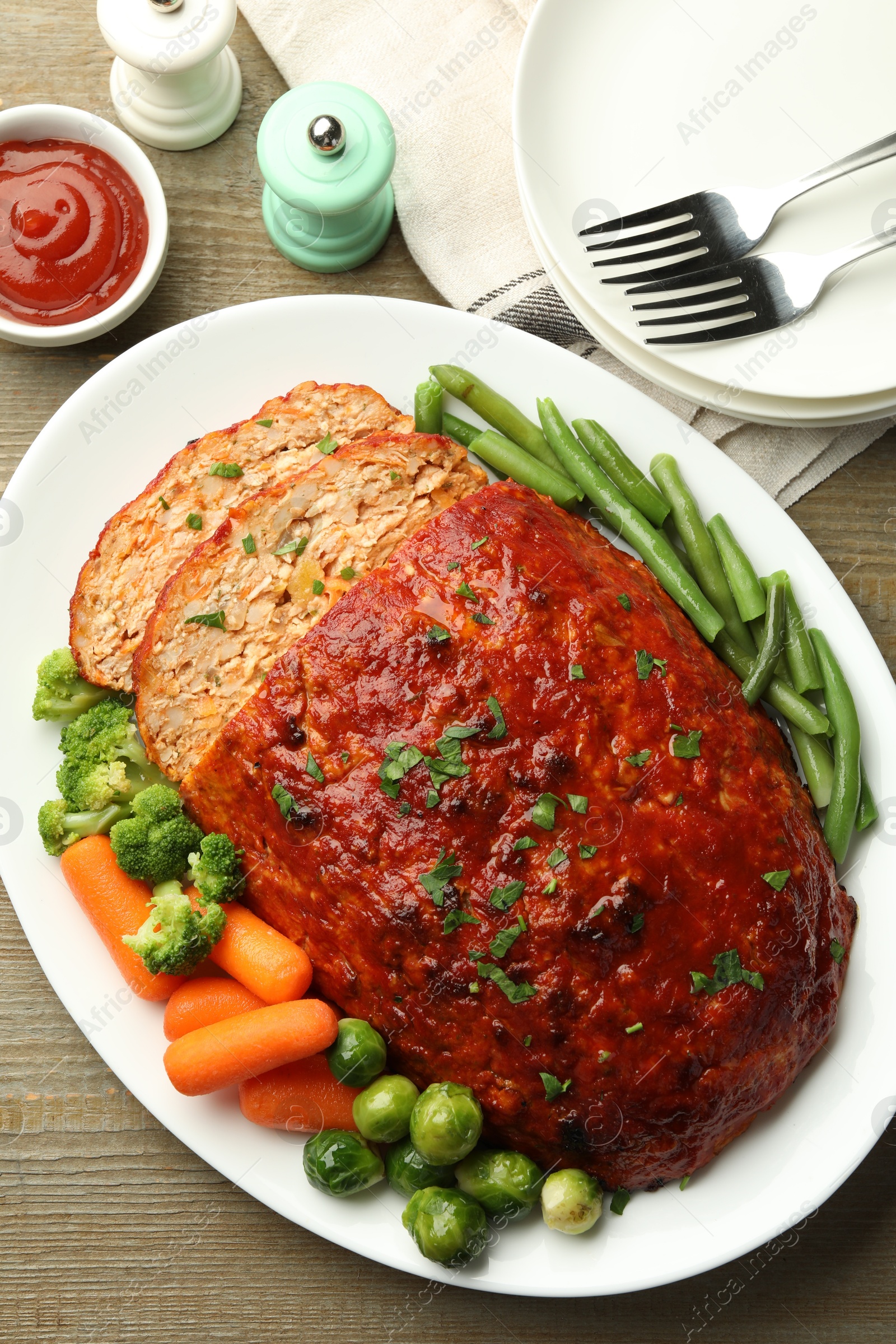 Photo of Delicious baked turkey meatloaf with vegetables served on wooden table, flat lay