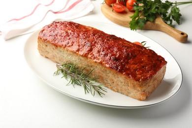 Photo of Delicious baked turkey meatloaf, rosemary, cherry tomatoes and parsley on white table, closeup