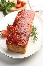 Photo of Delicious baked turkey meatloaf, rosemary, cherry tomatoes and parsley on white table, closeup