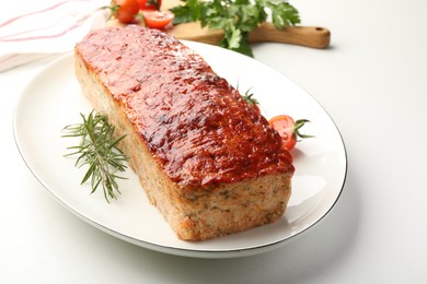 Delicious baked turkey meatloaf, rosemary, cherry tomatoes and parsley on white table, closeup