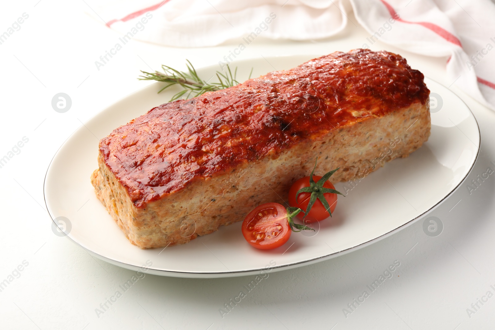 Photo of Delicious baked turkey meatloaf, rosemary and cherry tomatoes on white table, closeup