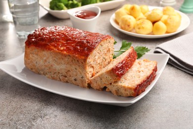 Photo of Delicious baked turkey meatloaf with vegetables served on grey table, closeup