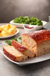 Photo of Delicious baked turkey meatloaf with vegetables served on grey table, closeup