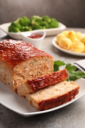 Photo of Delicious baked turkey meatloaf with vegetables served on grey table, closeup