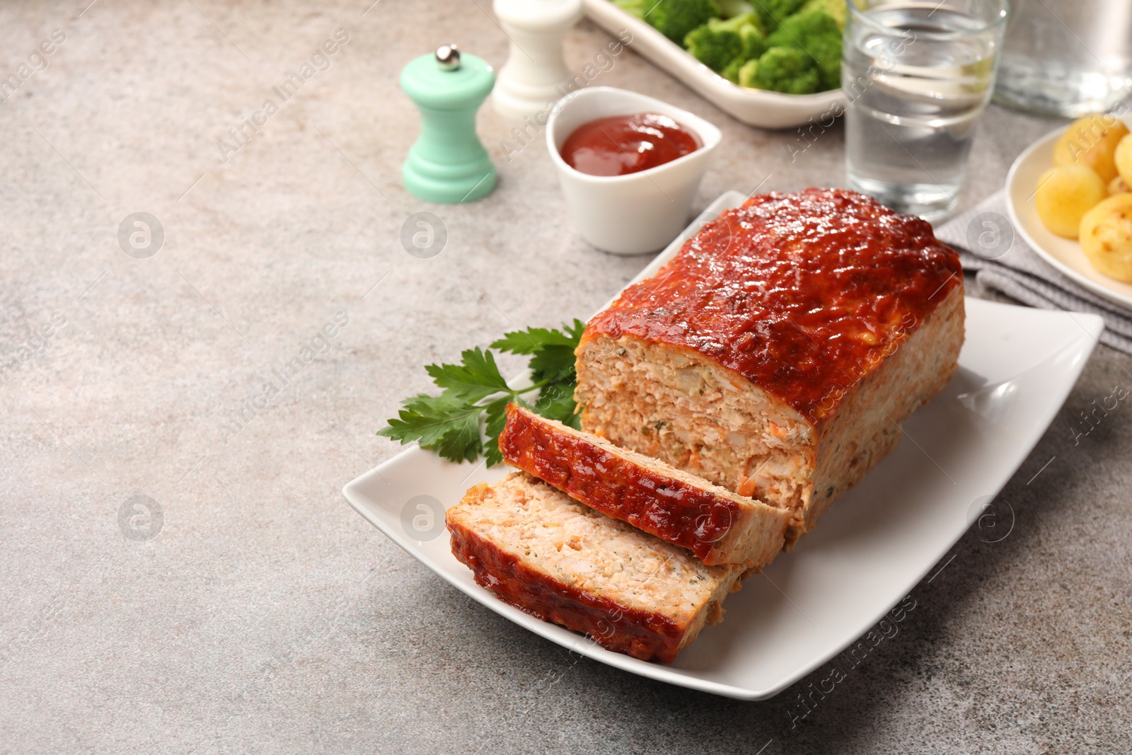 Photo of Delicious baked turkey meatloaf with vegetables served on grey table, closeup. Space for text