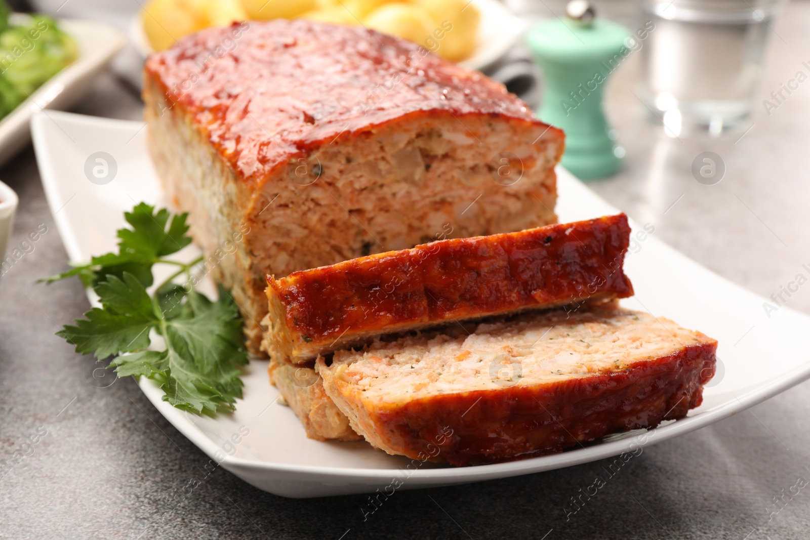 Photo of Delicious baked turkey meatloaf with parsley on grey table, closeup