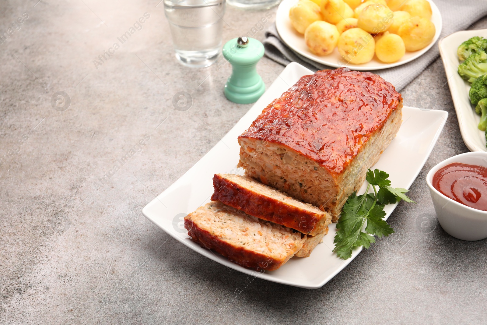 Photo of Delicious baked turkey meatloaf with vegetables served on grey table, closeup. Space for text