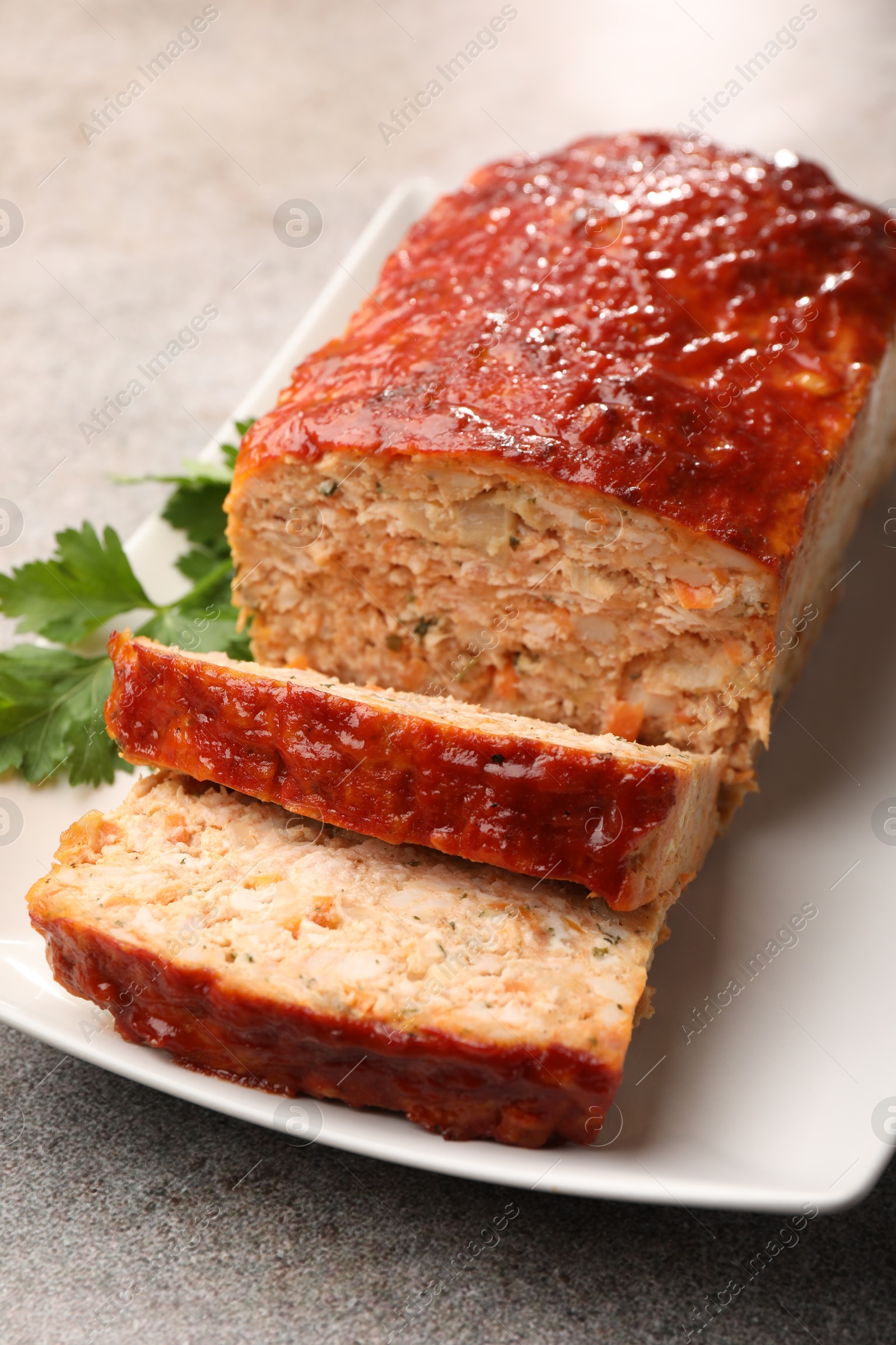 Photo of Delicious baked turkey meatloaf with parsley on grey table, closeup