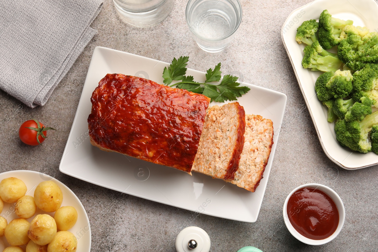 Photo of Delicious baked turkey meatloaf with vegetables served on grey table, flat lay