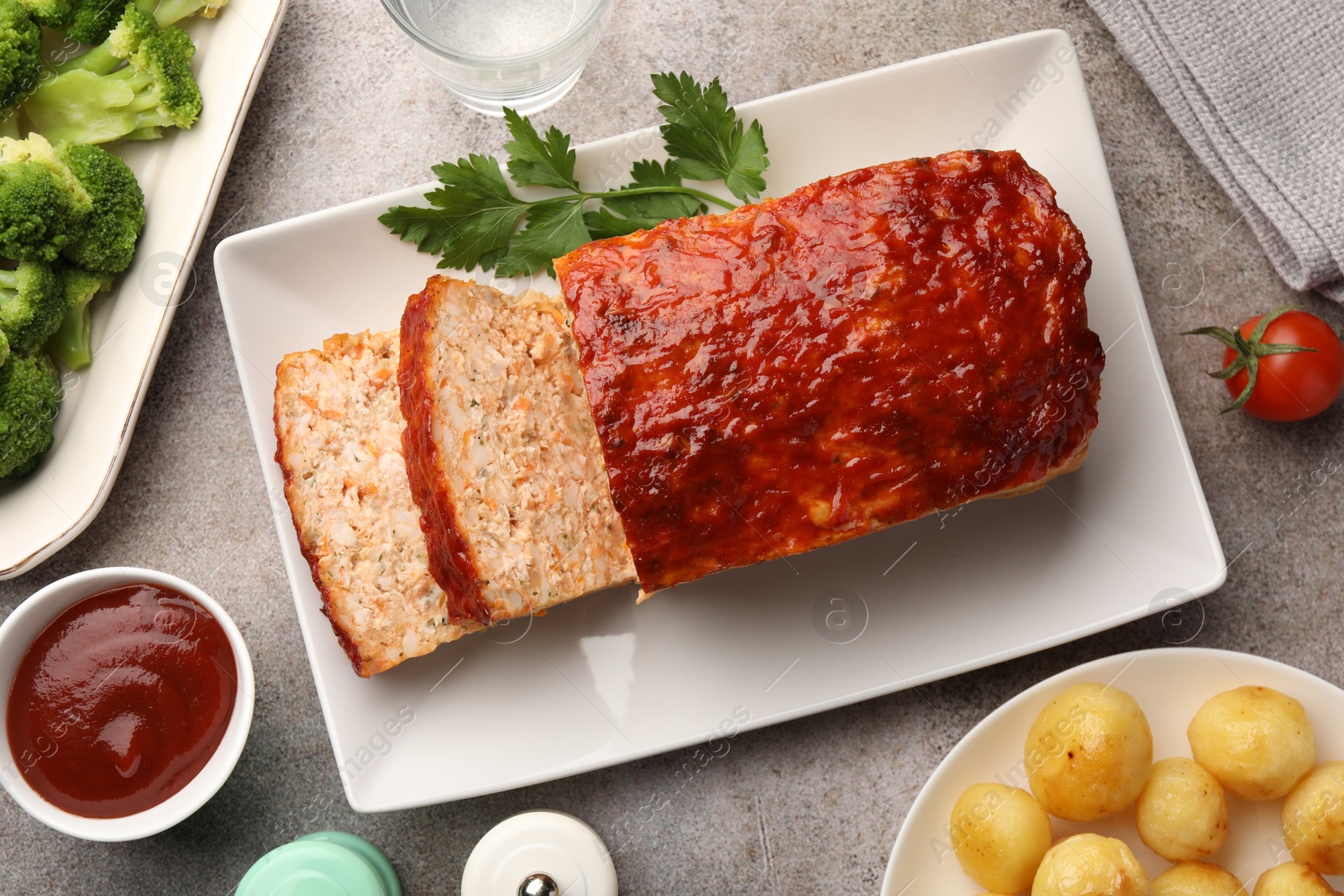 Photo of Delicious baked turkey meatloaf with vegetables served on grey table, flat lay