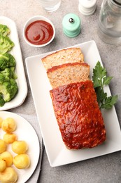 Photo of Delicious baked turkey meatloaf with vegetables served on grey table, flat lay