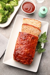 Photo of Delicious baked turkey meatloaf with vegetables served on grey table, flat lay