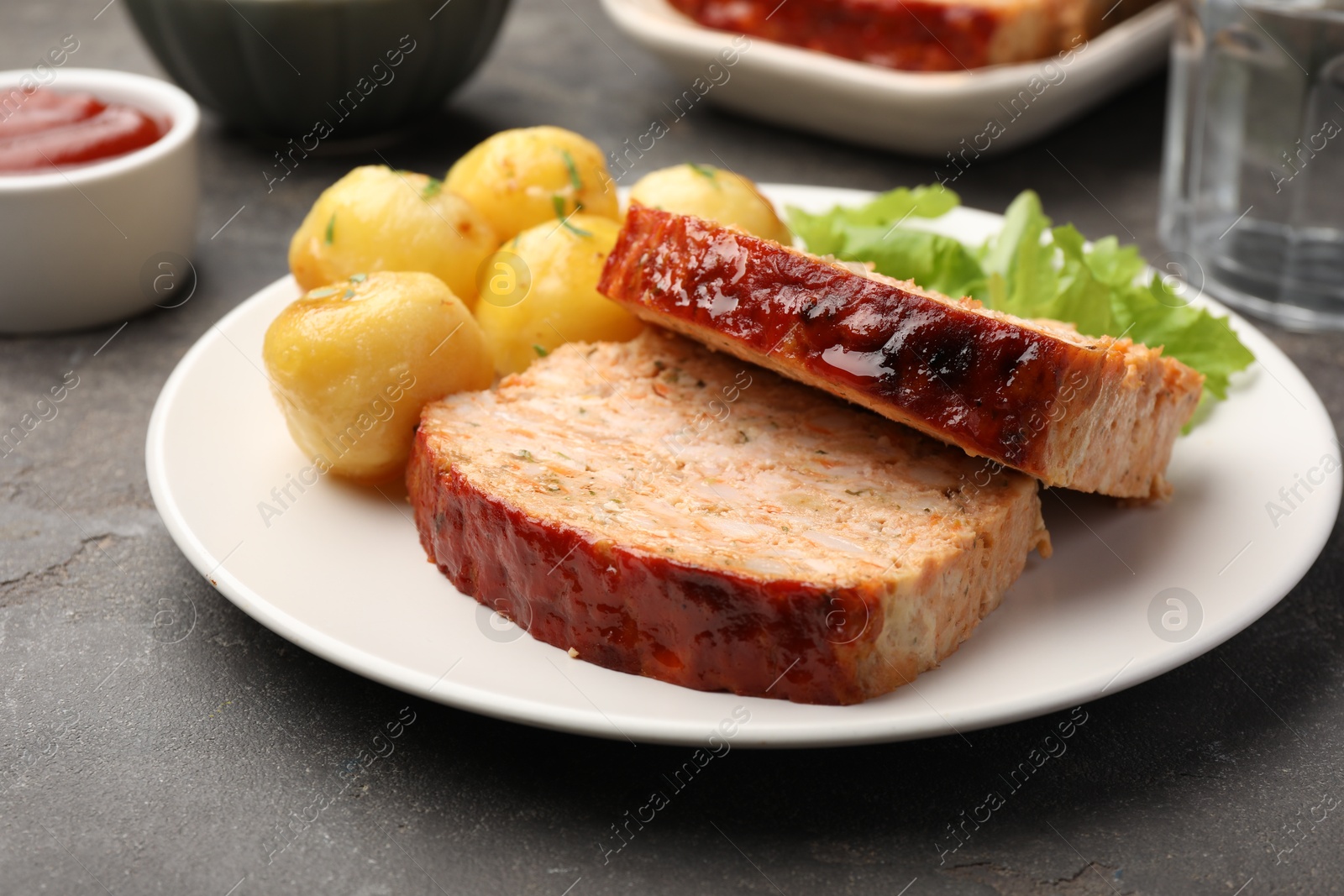 Photo of Delicious baked turkey meatloaf with potatoes served on grey table, closeup