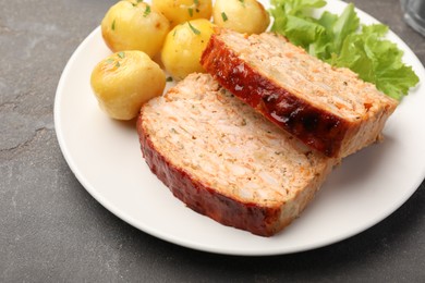 Photo of Delicious baked turkey meatloaf, potatoes and lettuce on grey table, closeup