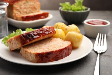 Photo of Delicious baked turkey meatloaf with potatoes served on grey table, closeup