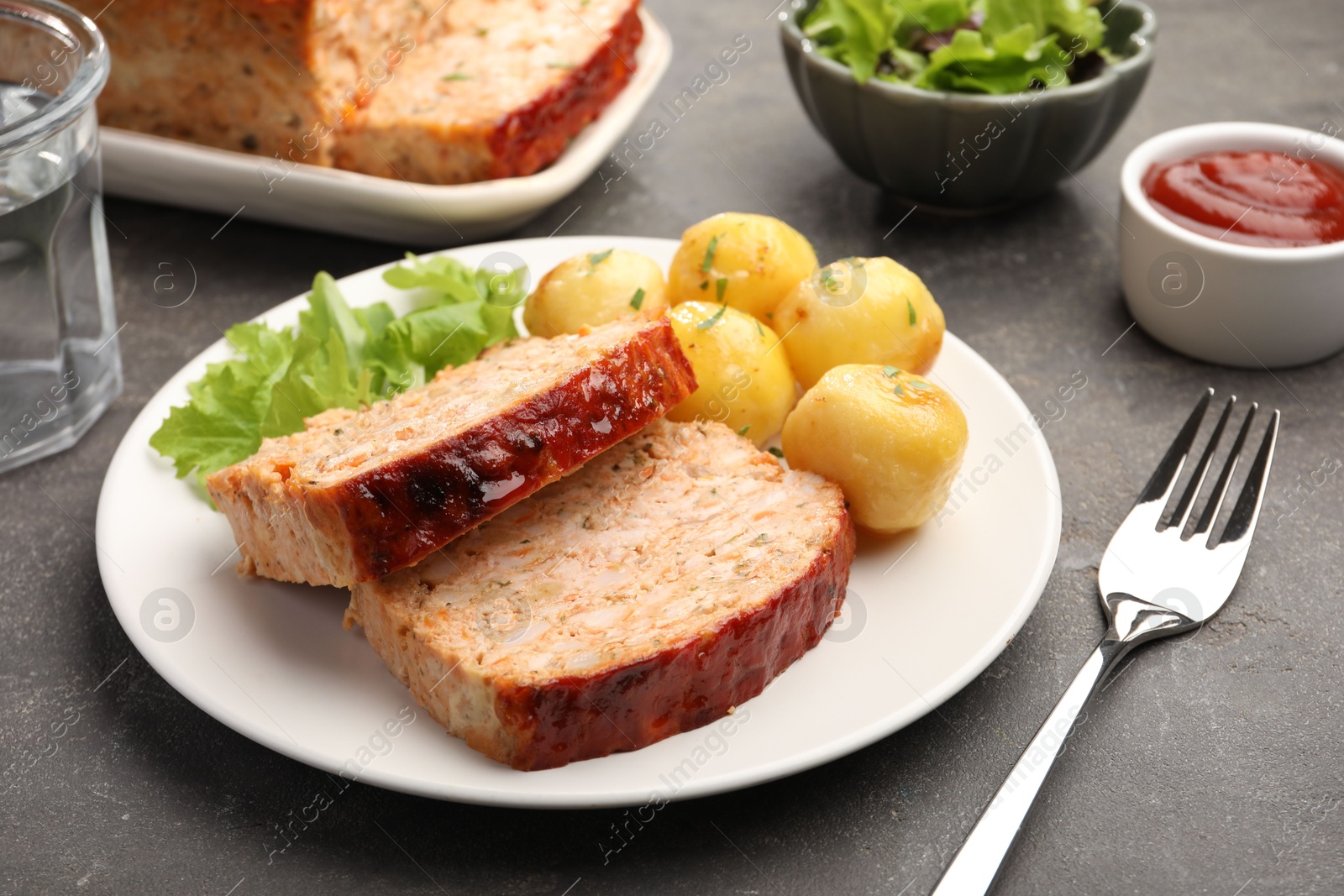 Photo of Delicious baked turkey meatloaf with potatoes served on grey table, closeup