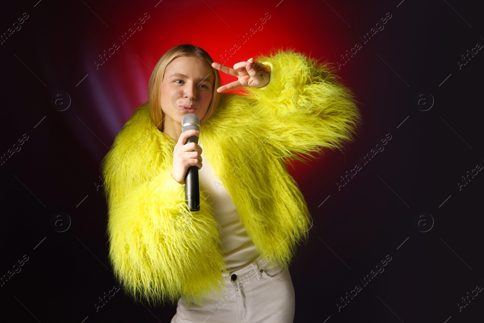 Photo of Talented singer in faux fur performing on dark background with red light