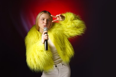 Photo of Talented singer in faux fur performing on dark background with red light