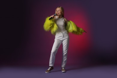 Talented singer in faux fur performing on dark background with pink light