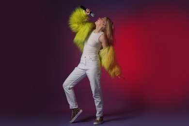 Talented singer in faux fur performing on dark background with pink light