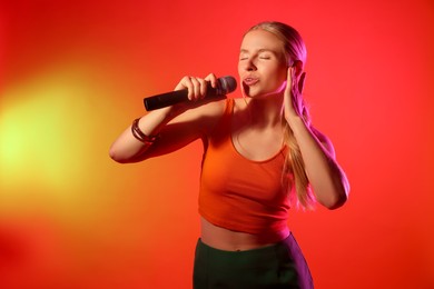 Photo of Talented singer performing on red background with yellow light