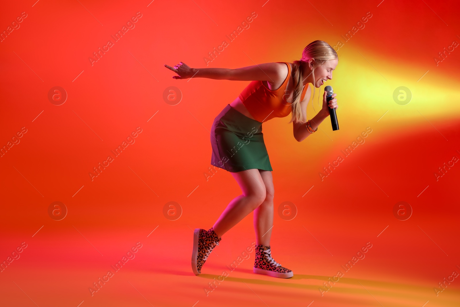 Photo of Talented singer performing on red background with yellow light. Space for text