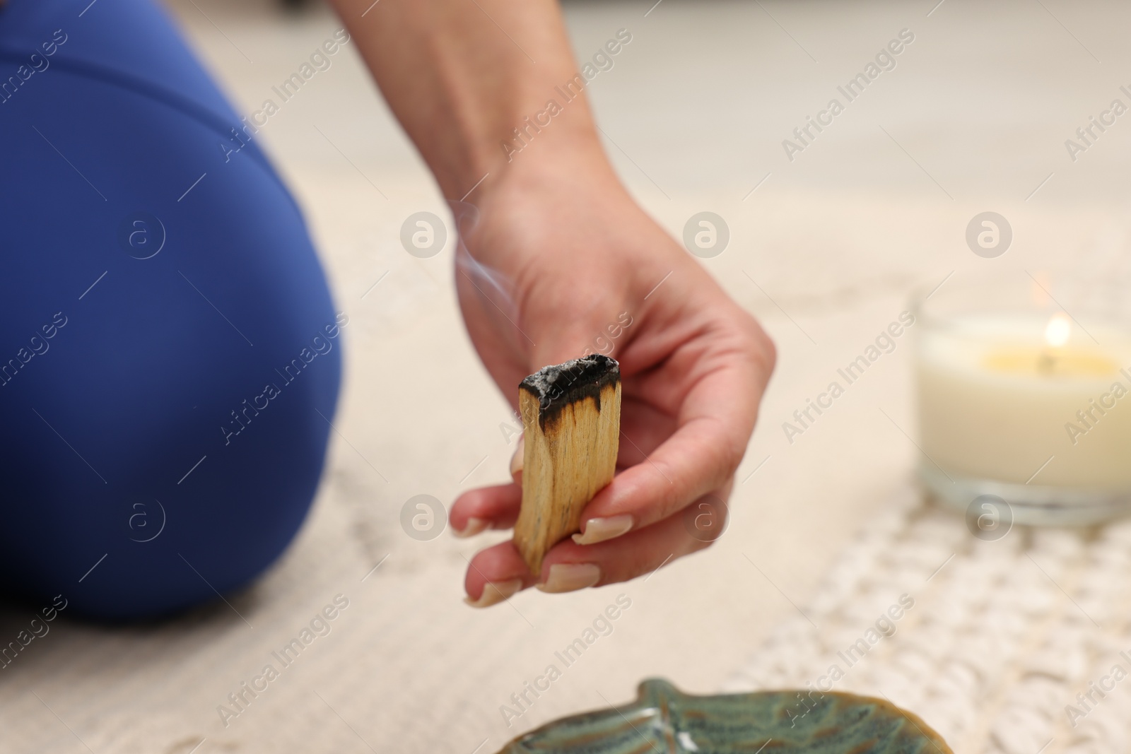 Photo of Woman with smoldering palo santo stick at home, closeup