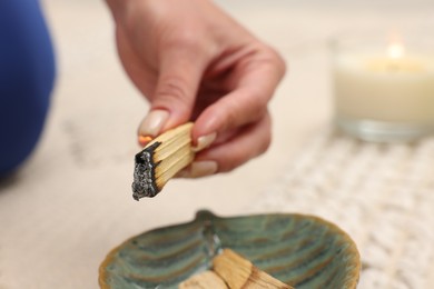 Photo of Woman with burning palo santo stick at home, closeup